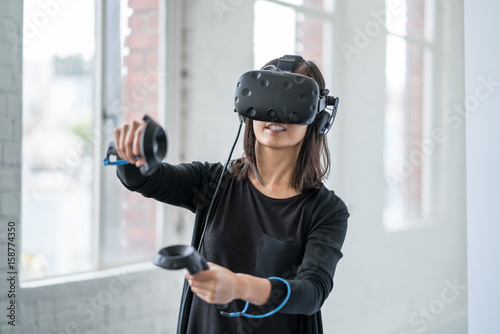 An asian woman wearing a virtual reality headset. © db