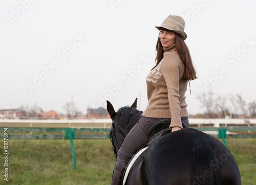  Woman riding horse, beige pullover, jeans, hat, close up © genuimous