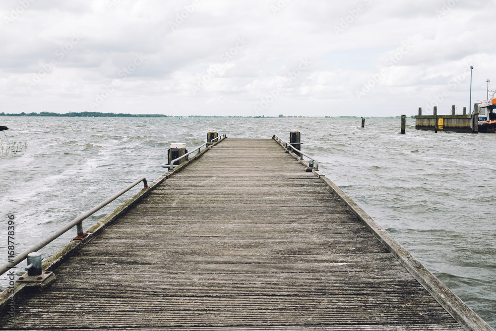 Empty wooden pier with dark stormy clouds over Northern  Sea in The Netherlands