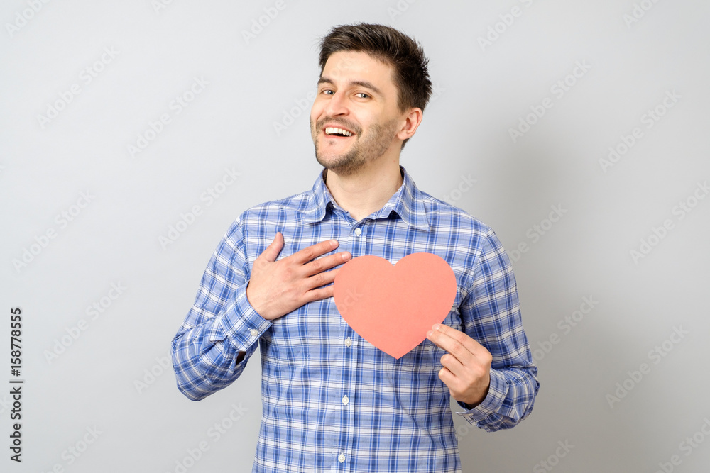 Portrait of smiling man holding red paper heart Portrait of smiling man holding red paper heart