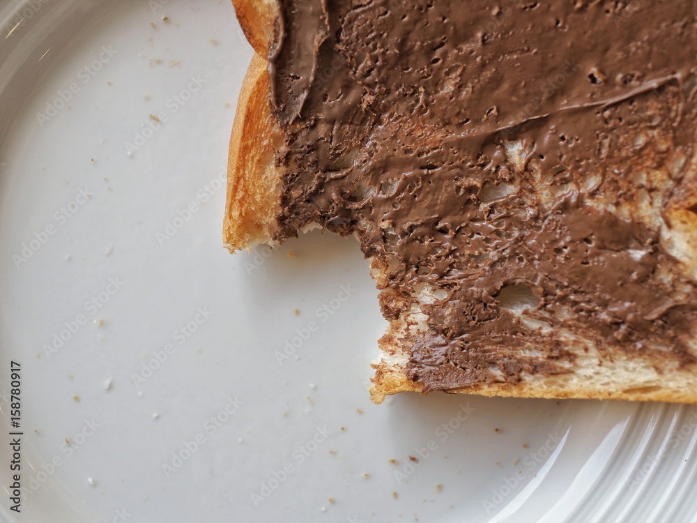 Fototapeta premium Sliced bread and chocolate spread with a bite taken.