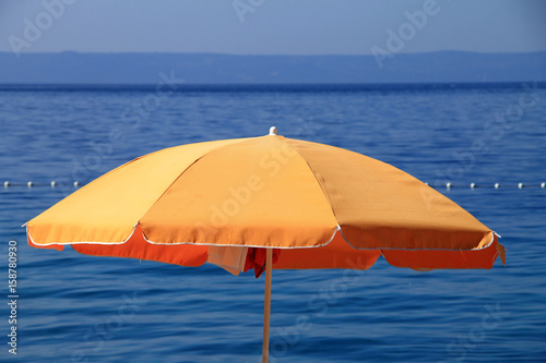 Orange beach umbrella near the Adriatic sea in Brela , Croatia 