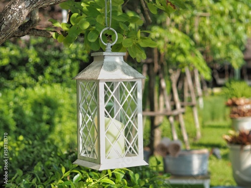 White Iron lantern hanging on tree in the garden. Concept of exterior decoration.