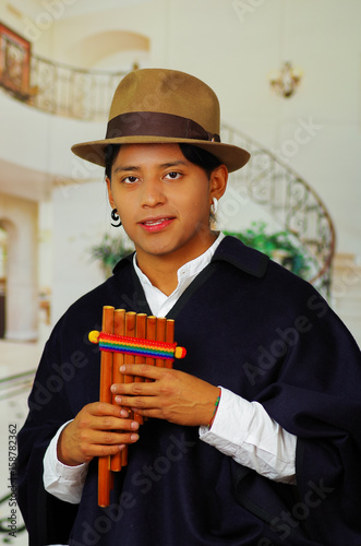 Indigenous young man from Otavalo, Ecuador, playing the rondador photo