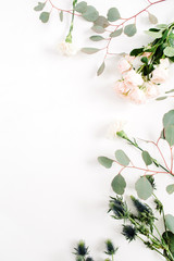 Beige rose flowers, eringium flower, eucalyptus branches on white background. Flat lay, top view. Floral background