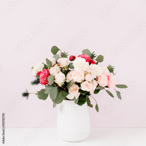 Beautiful flowers bouquet in flowerpot near pale pastel pink wall. Floral lifestyle composition.