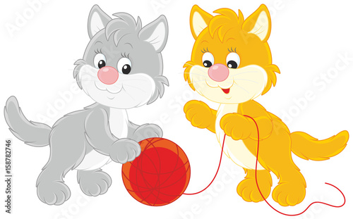 Little kittens playing with a red clew of yarn