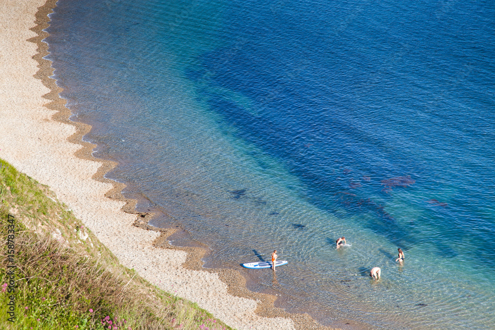 Obraz premium people enjoying a hot summer day on a beautiful hidden beach on the Jurassic Coast of Dorset, UK - Britiish summer holiday destination