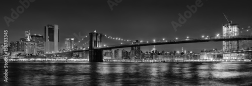 Black and white panoramic photo of Brooklyn Bridge at Night, NYC.
