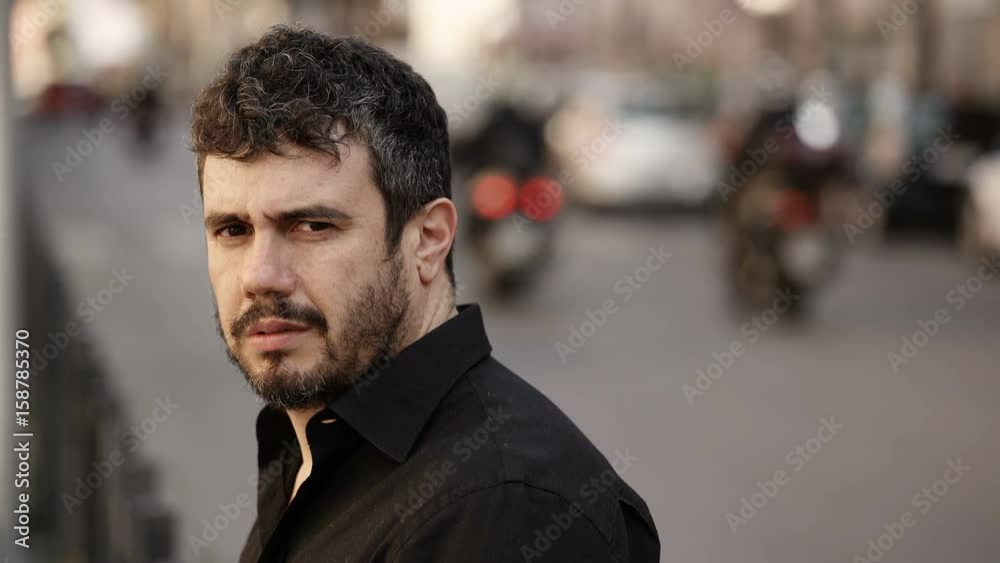 serious latin man in the street,turning his head and staring the camera serious latin man in the street,turning his head and staring the camera