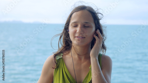 Beautiful dreamy young woman listening to music on headphones on the sailing ship © emaria