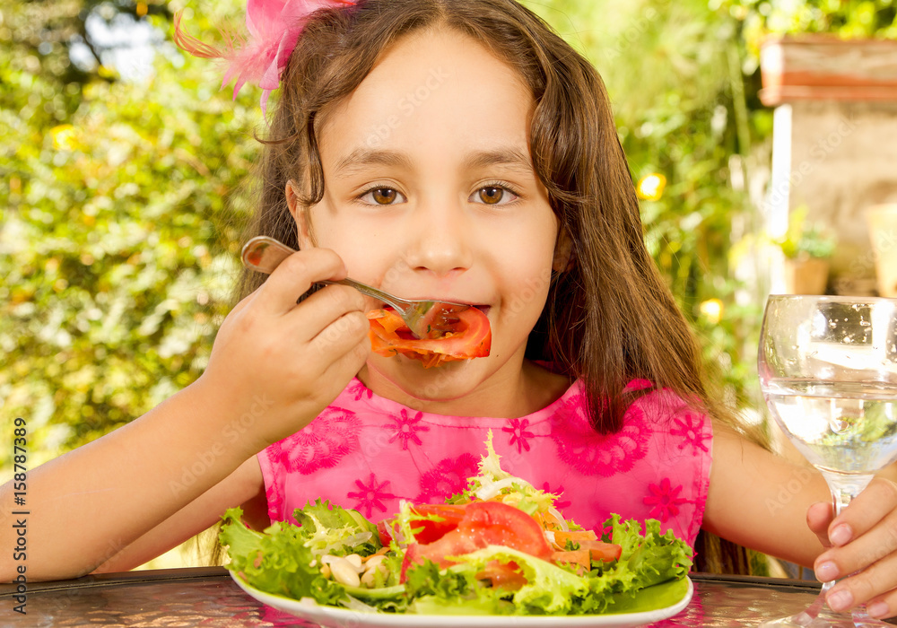 Close up of beautiful girl, eating a healthy salad and drink a glass of water, in a garden background Close up of beautiful girl, eating a healthy salad and drink a glass of water, in a garden background