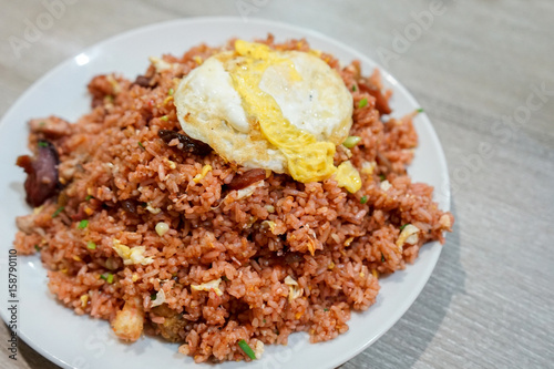 Fried rice with pork and fried egg on a plate and wooden table. Thai food