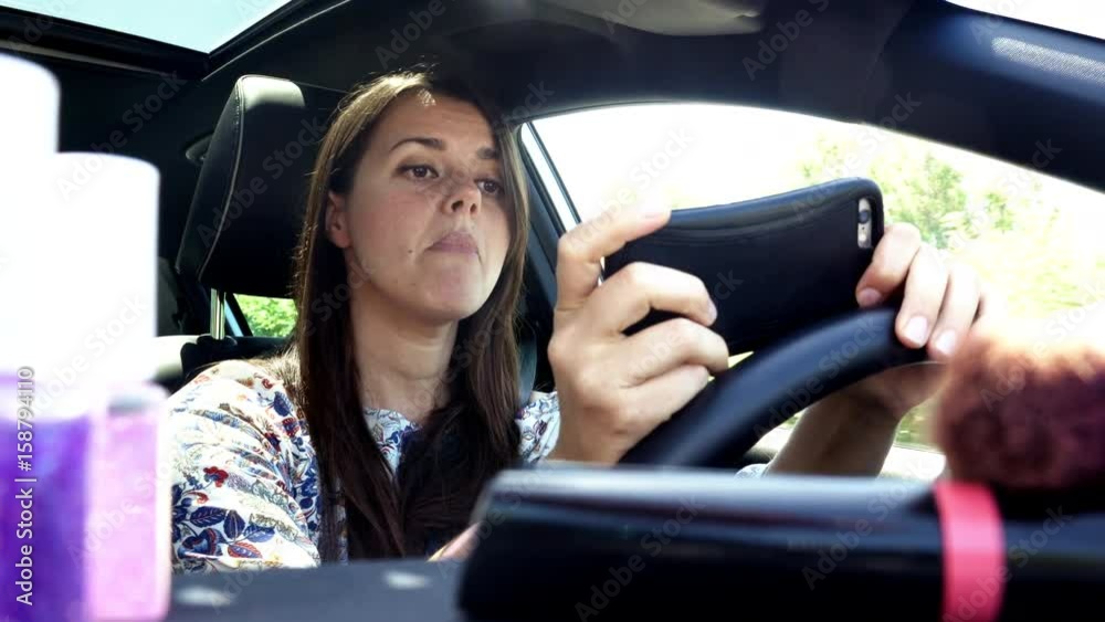 Woman texting message with cell phone while driving car dangerous