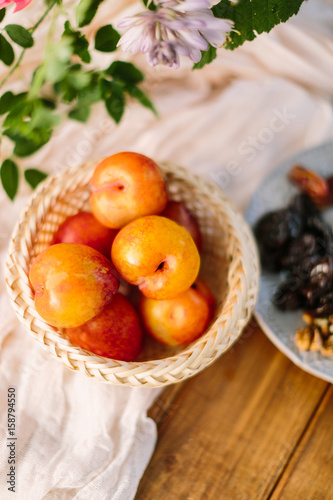 healthy life  nutrition  diet  food  country concept - close-up of red-yellow apricots lying in straw basket on snow white draping on wooden table