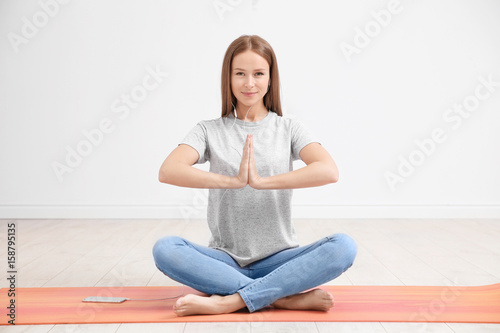 Young woman practicing yoga and listen to music at home