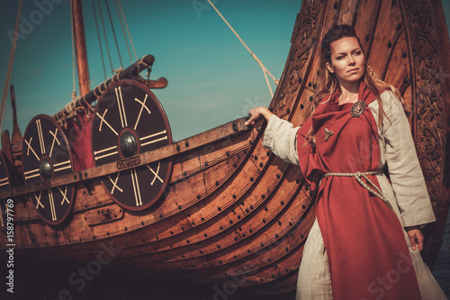 Foto Viking woman in traditional clothes near drakkar