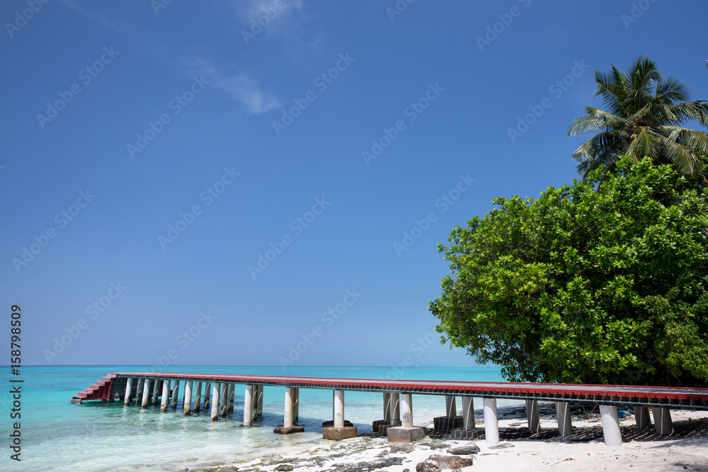 Tropical travel destinations with Maldives island and wooden wharf