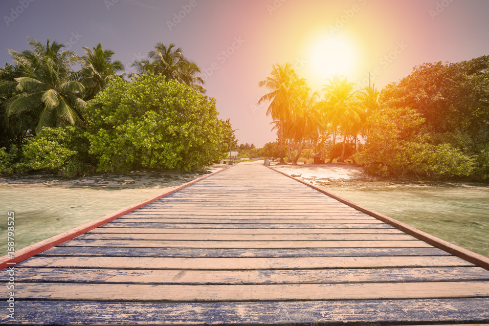 Tropical travel destinations with Maldives island and wooden wharf Tropical travel destinations with Maldives island and wooden wharf