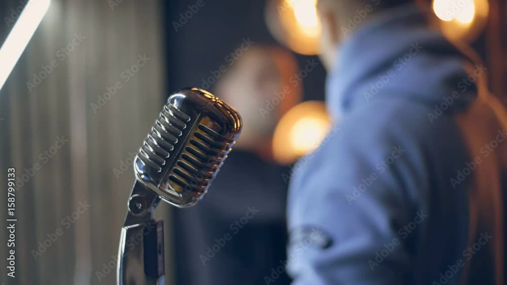 Retro microphone on stage. Close up of vintage radio microphone. Silver microphone in retro style. Old microphone on stage against background of stage lighting