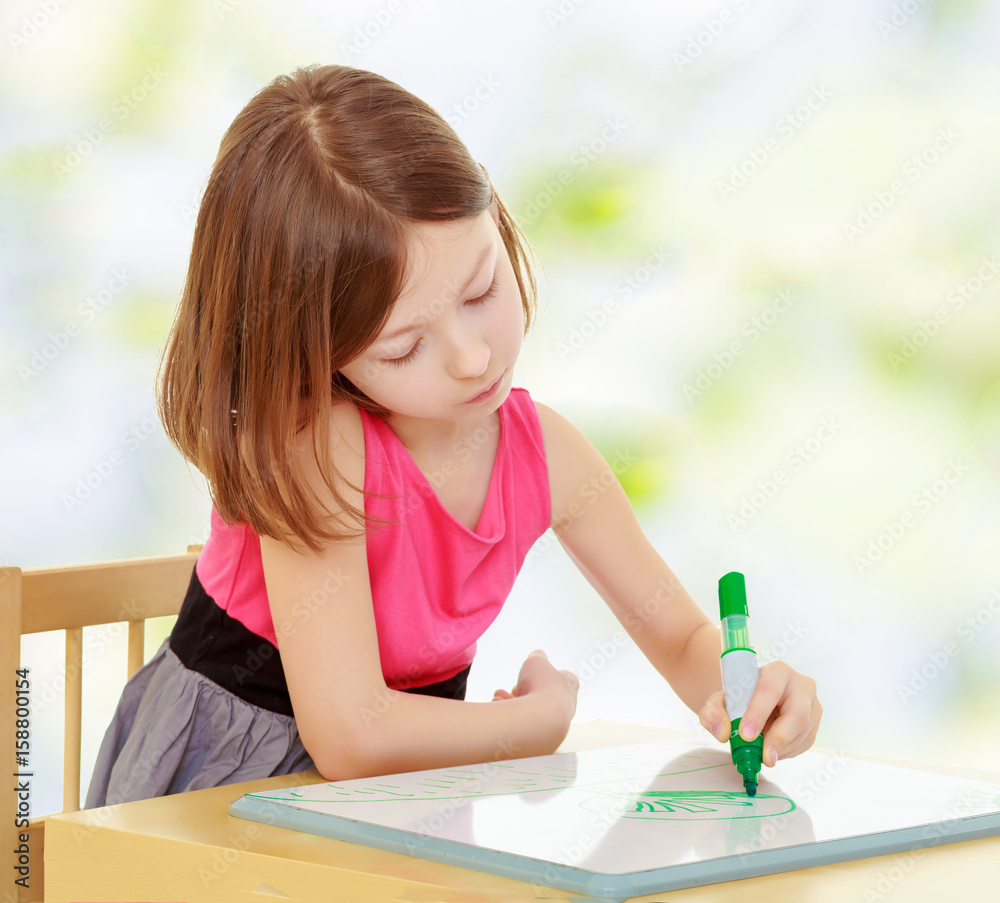 little girl draws with marker sitting at the table. little girl draws with marker sitting at the table.