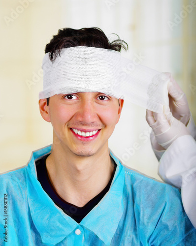 Portrait of a young man with trauma in his head and elastic bandaged around his head photo