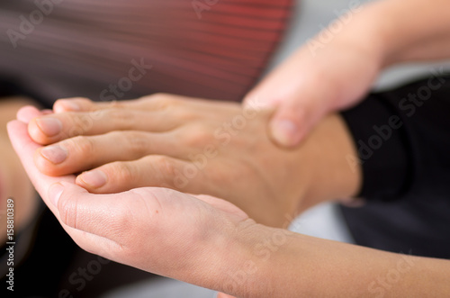 Close up of a massage physiotherapist doing hand massage of a male athlete, in medical office background