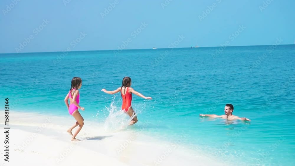 Happy family at tropical beach have fun. Father and little kids enjoy time together swimming in the sa. SLOW MOTION