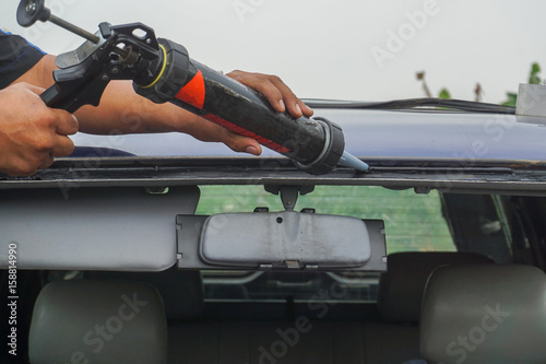 Glazier using tools repairing to fix crack broken windshield, windscreen on the front window glass of the machine car accident.