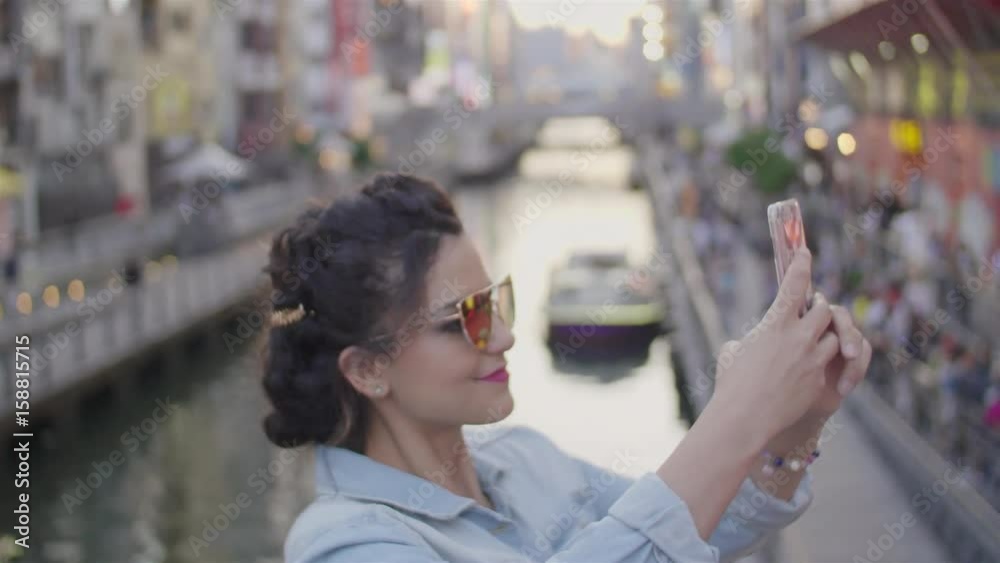 Young women taking photos of Osaka Dotombori bridge at Sunset