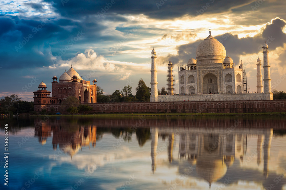 Fototapeta premium Taj Mahal with a moody sunset sky on the banks of river Yamuna. Taj Mahal is a white marble mausoleum designated as a UNESCO World heritage site at Agra, India.