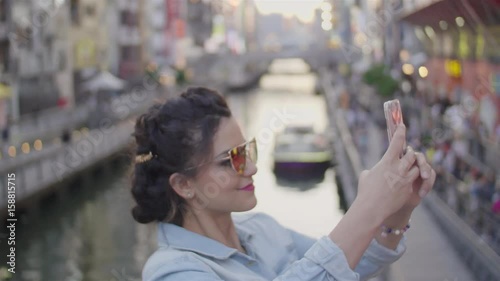 Young women taking photos of Osaka Dotombori bridge at Sunset photo