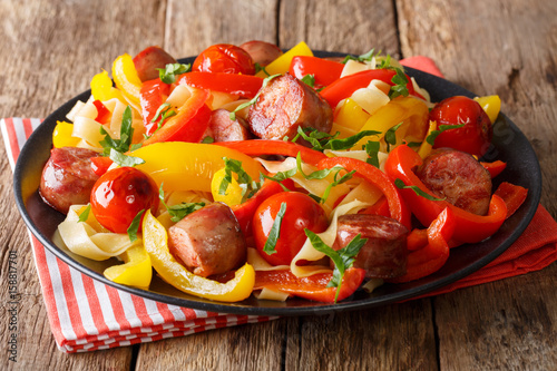 Pasta fettuccine with bell pepper and sausages close-up on a plate. Horizontal photo