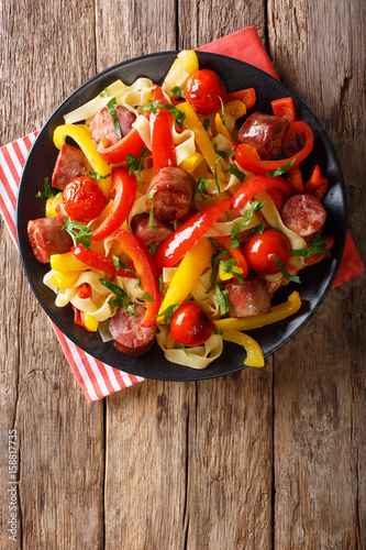 Pasta fettuccine with bell pepper and sausages close-up on a plate. vertical top view