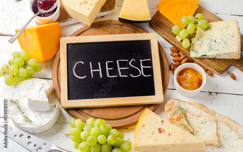Cheese served with grapes, jam, bread and nuts on a wooden background