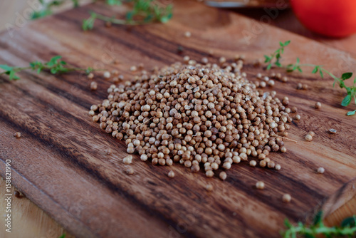 pile of dried coriander seeds on wooden cutting board © yodaswaj