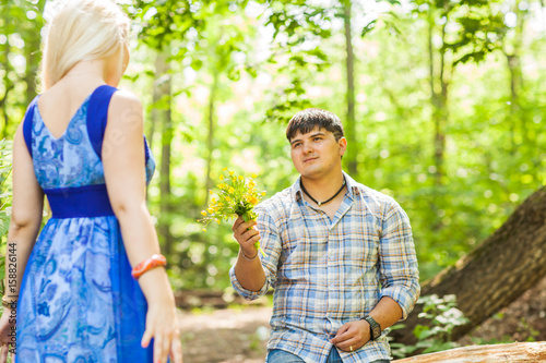 Young man giving a flower dandelion to girlfriend outdoors