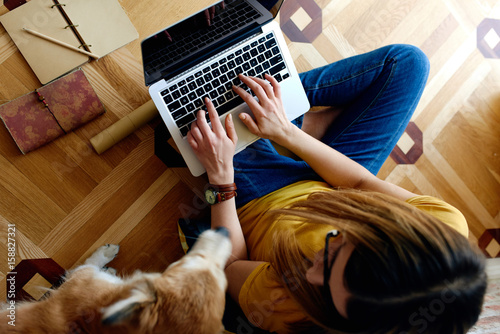 Young woman studying with her dog on the floor