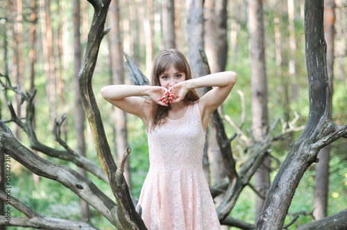 портрет девушки в персиковом платье в лесу, она закрывает лицо руками