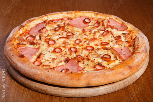 Italian pizza on the table, pepperoni, spices, tomatoes, cheese