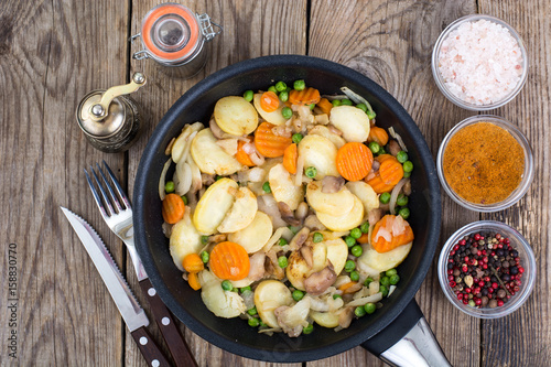 Potatoes fried with vegetables and mushrooms in frying pan