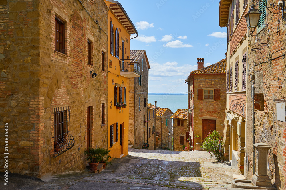 Beautiful narrow alley with traditional historic houses at old city in Tuscany