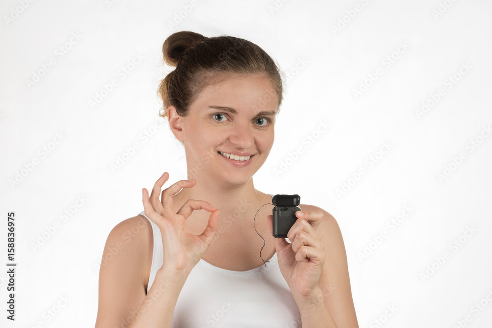 Hygiene of the oral cavity. Young girl cleans teeth with floss, smiling and showing okay sign on a background. Hygiene of the oral cavity. Young girl cleans teeth with floss, smiling and showing okay sign on a background.