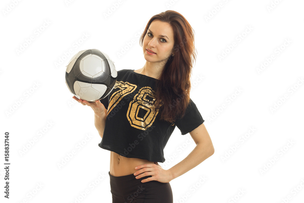 athletic young girl stands with a soccer ball and keeping his hand on the side athletic young girl stands with a soccer ball and keeping his hand on the side