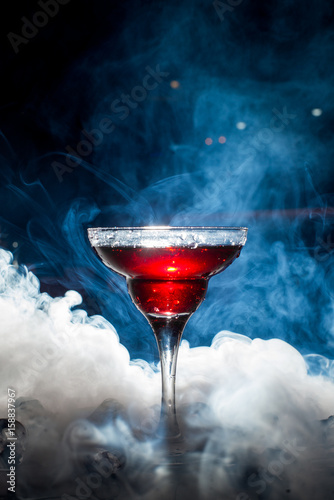 red cocktail with ice vapor, blue background