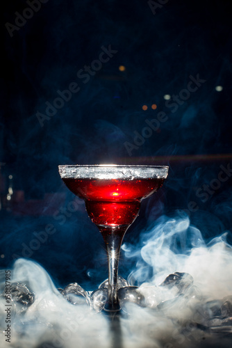 red cocktail with ice vapor, blue background