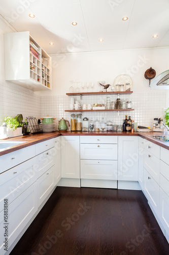 kitchen interior with dark wooden floor and white cupboards © annaia