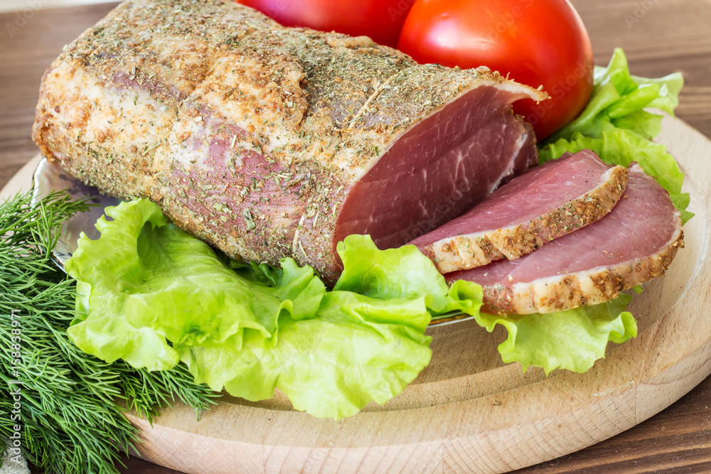Slices of smoked meat with lettuce and tomato on a wooden board. Selective focus. Horizontal. Slices of smoked meat with lettuce and tomato on a wooden board. Selective focus. Horizontal.