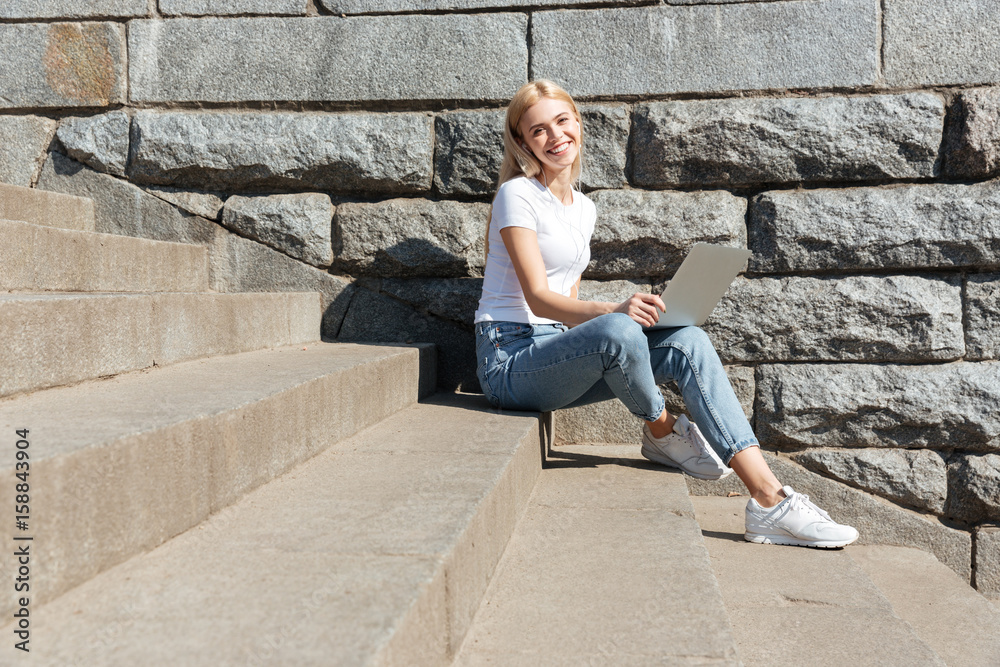 Young pretty woman sitting on stairs with laptop computer Young pretty woman sitting on stairs with laptop computer