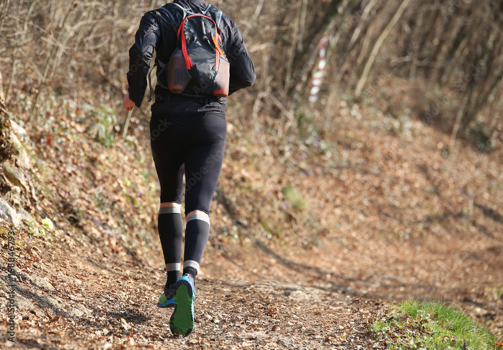 Leg of athlete runner from behind during racing on the trail in Leg of athlete runner from behind during racing on the trail in